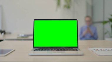 Laptop with Green Screen on Desk in Office