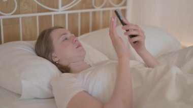 genç kadın yatakta yatan Smartphone kullanarak