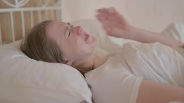 Yatakta yatan baş ağrısı olan genç bir kadının yan görüntüsü.