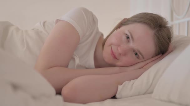 笑顔の若い女性が横にベッドに横たわっている — ストック動画