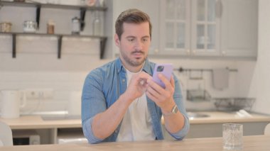 Genç adam iş yerinde akıllı telefon kullanıyor.