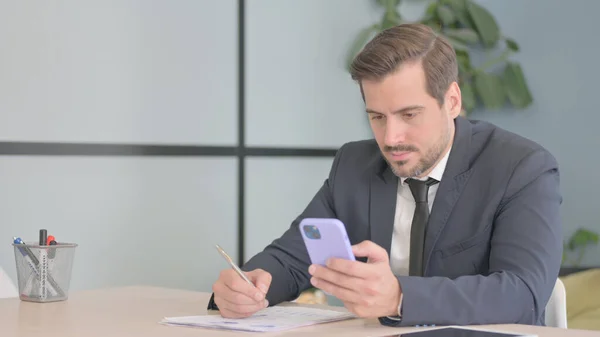 Businessman Doing Paperwork Using Smartphone — Stock Photo, Image