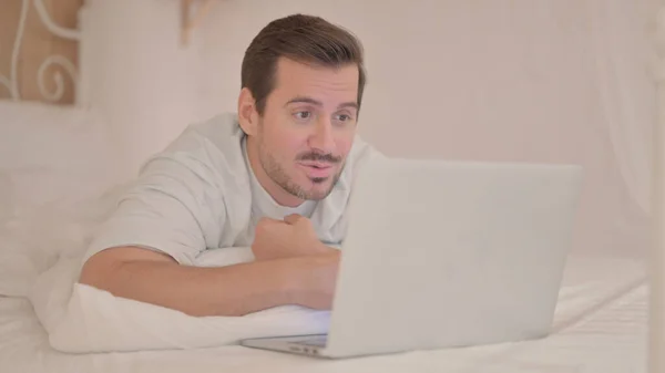 Ung Man Gör Videochatt Laptop Medan Ligger Mage Sängen — Stockfoto