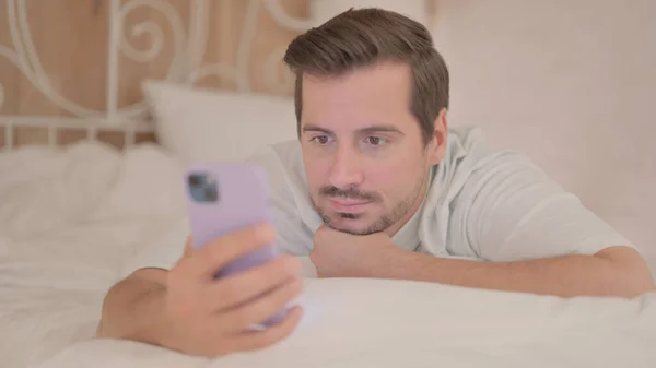 Homem Jovem Usando Smartphone Enquanto Deitado Estômago — Fotografia de Stock