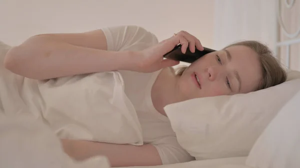 Genç Kadın Yatakta Telefonda Konuşuyor — Stok fotoğraf