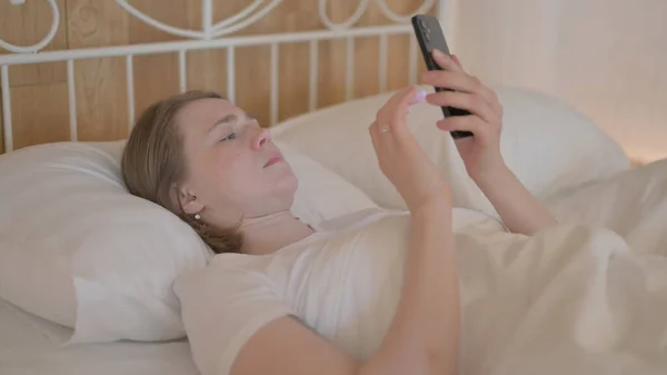 stock image Young Woman using Smartphone while Lying in Bed