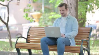 Bilek ağrısı olan genç adam laptopta çalışıyor.