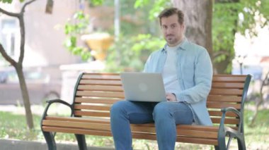 Dışarıdaki Laptop 'u kullanırken Genç Adam Kamerayı Gösteriyor