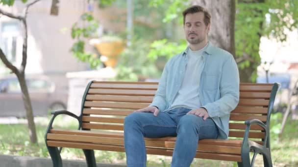 Schwerer Junger Mann Sitzt Draußen Auf Bank — Stockvideo