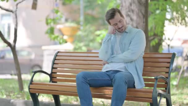 Schlafender Junger Mann Sitzt Draußen Auf Bank — Stockvideo