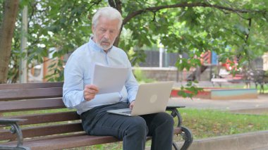 Dokümanlar ve Diz üstü bilgisayar üzerine çalışan kıdemli yaşlı adam.