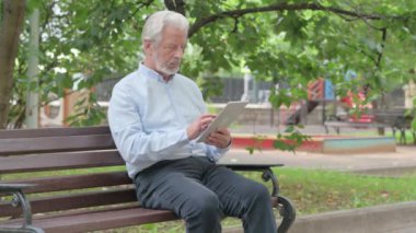 Bir bankta otururken Tablette Başarı Kutlaması Yapan Yaşlı Yaşlı Adam