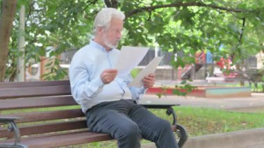Dışarıda Otururken Kıdemli Yaşlı Adam Belgeleri Okuyor