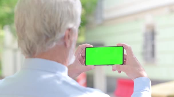 有绿色屏风户外的老年男子手持电话 — 图库视频影像