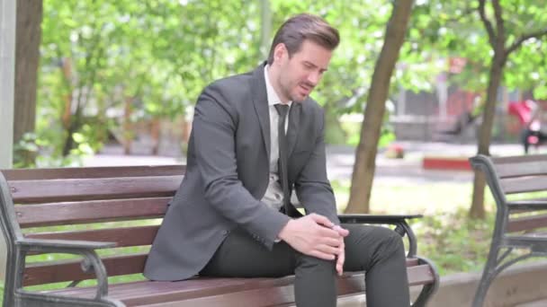 Junger Geschäftsmann Sitzt Mit Knieverletzung Auf Bank — Stockvideo