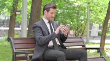 Genç İşadamı Smartphone 'da Dışarda Bir Bençte Otururken Kaybından Şok Oldu