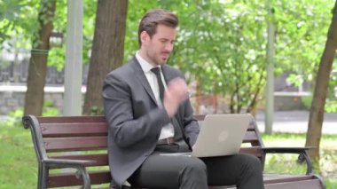 Dişi ağrılı genç iş adamı dışarıda dizüstü bilgisayarda çalışıyor.