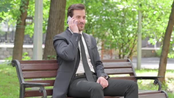 Genç Şadamı Bir Bankta Otururken Telefonda Konuşuyor — Stok video