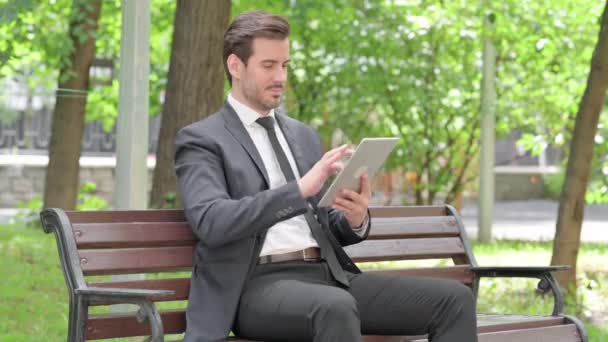 ベンチに屋外に座っている間タブレットを使用している若いビジネスマン — ストック動画