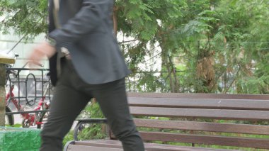 Orta yaşlı işadamı Bench 'te oturduktan sonra ayrılıyor.