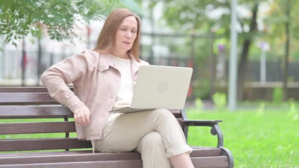 长者坐在户外时使用背痛手提电脑 — 图库视频影像