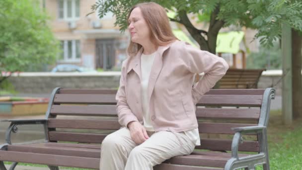Σύγχρονη Ηλικιωμένη Γυναίκα Πόνο Στην Πλάτη Κάθεται Στο Bench — Αρχείο Βίντεο