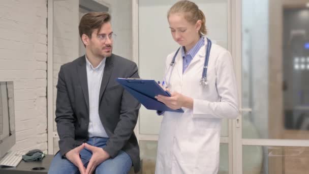 Vrouwelijke Doctor Writing Informatie Tijdens Het Luisteren Patiënt Kliniek — Stockvideo