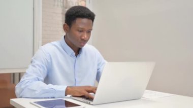 Ofiste dizüstü bilgisayarla çalışırken kameraya bakan Afrikalı İşadamı