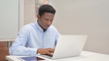 Ofiste Dizüstü bilgisayarla çalışırken kameraya gülümseyen Afrikalı İşadamı