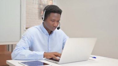 Kulaklıklı gülümseyen Afrikalı Çağrı Merkezindeki Kameraya Bakıyor