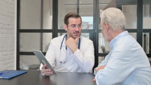 Молодий Лікар Розмовляє Старим Пацієнтом Обговорюючи Цифровий Медичний Звіт — стокове відео