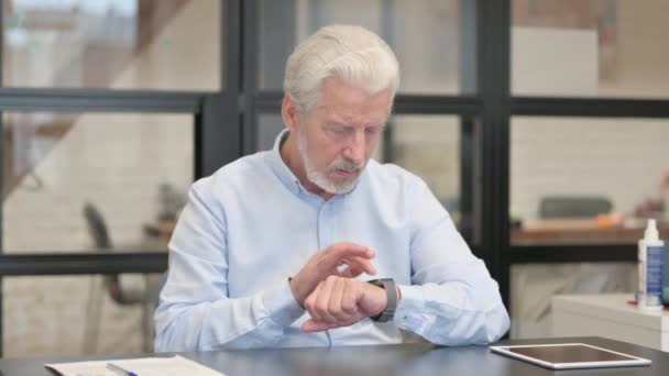 Παλιά Επιχειρηματίας Χρησιμοποιώντας Smart Watch Στο Γραφείο — Αρχείο Βίντεο