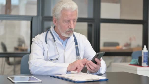 Médico Senior Usando Teléfono Para Papeleo — Vídeos de Stock