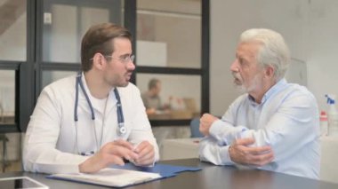 Dirsek ağrısı olan yaşlı adam ortopedik kıdemli doktorla konuşuyor.