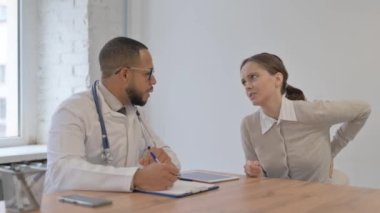 Sırt ağrısı olan Afrikalı bir adam ortopedi doktoruna danışmanlık yapıyor.