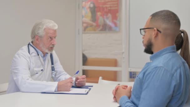 Starszy Lekarz Rozmawiający Parą Klinice — Wideo stockowe