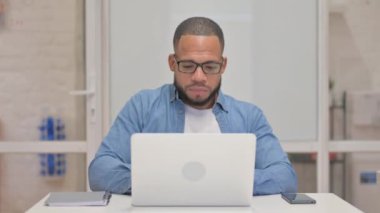 Dizüstü bilgisayarda çalışırken kameraya bakan karışık ırk adamı