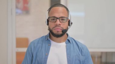 Kulaklıklı Afrikalı Çağrı Merkezindeki Kameraya Bakıyor