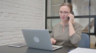 Kızgın yaşlı kadın telefonda konuşuyor.