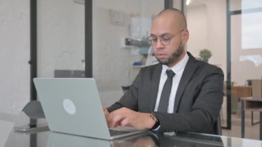 Karışık Yarış İşadamı Bilgisayarda çalışırken Kameraya Bakıyor