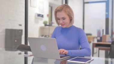 Ofiste dizüstü bilgisayarla uğraşırken Başparmakları Düşük Genç Kadın