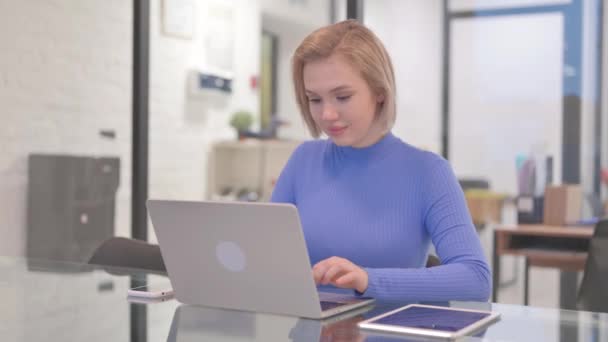 在办公室的笔记本电脑上工作时 年轻女性在相机前微笑 — 图库视频影像