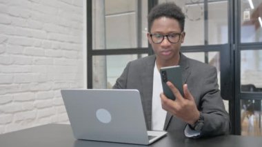Dizüstü bilgisayarlı Genç Afrikalı Adam Telefonu Kullanıyor