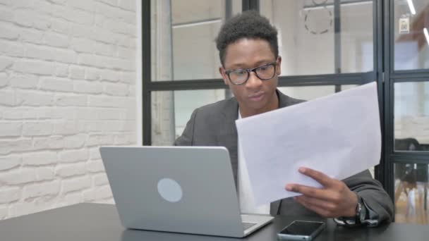 Νεαρός Αφρικανός Που Γιορτάζει Ενώ Εργάζεται Φορητό Υπολογιστή Και Έγγραφα — Αρχείο Βίντεο