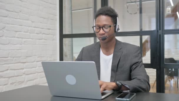 Ung Afrikansk Man Med Headset Arbetar Laptop — Stockvideo