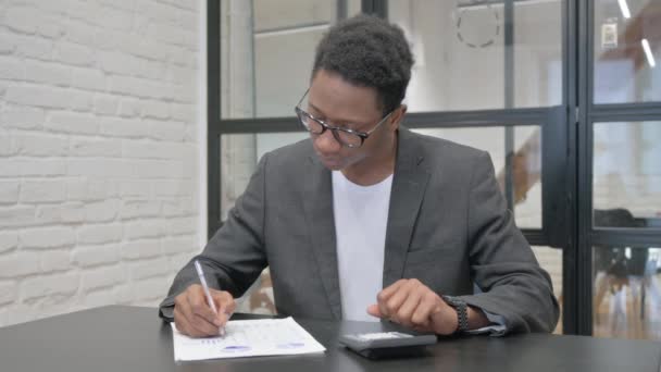 紙ワークのための計算をする若いアフリカ人男性 — ストック動画