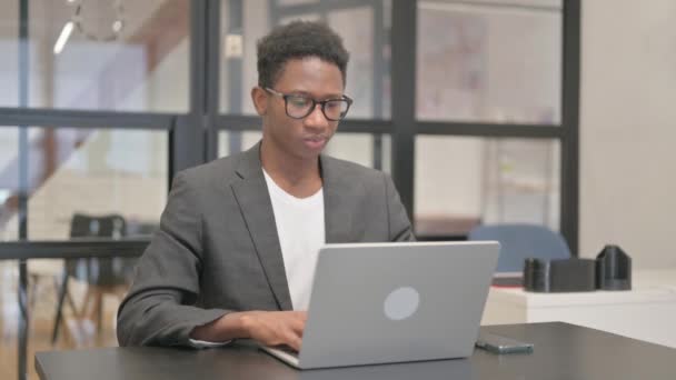 アフリカ系アメリカ人男性がノートパソコンで作業中にカメラを指して — ストック動画