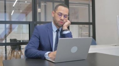 Dizüstü bilgisayarın önünde uyuyan takım elbiseli yorgun adam.