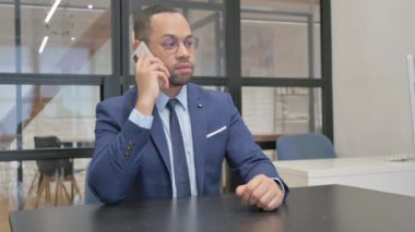 Takım elbiseli adam telefonda konuşuyor.