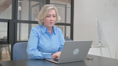 Dizüstü bilgisayarda çalışırken Başparmaklarını Gösteren Yaşlı Yaşlı Kadın